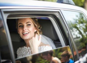 woman wearing wedding dress smiling inside car