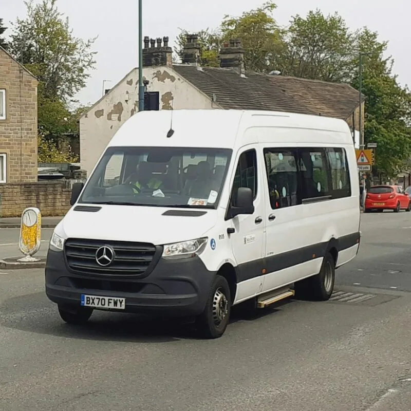 a white van driving down a street next to tall buildings